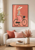 Fahrrad Poster mit Radfahrerin in rosa Rock und Sonnenhut im schwarzen Rahmen über hellem Sofa